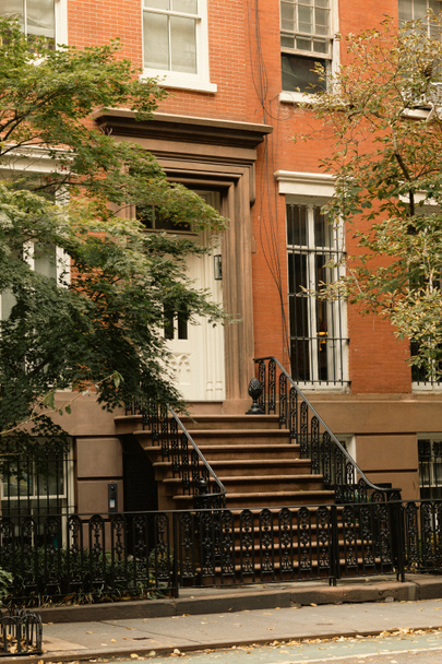 brick house with white windows and entrance with stairs near autumn trees on street in New York City - Фото, зображення