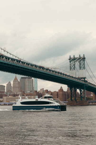 moderno yate en el río Hudson bajo el puente de Manhattan y cielo nublado en la ciudad de Nueva York - Foto, imagen