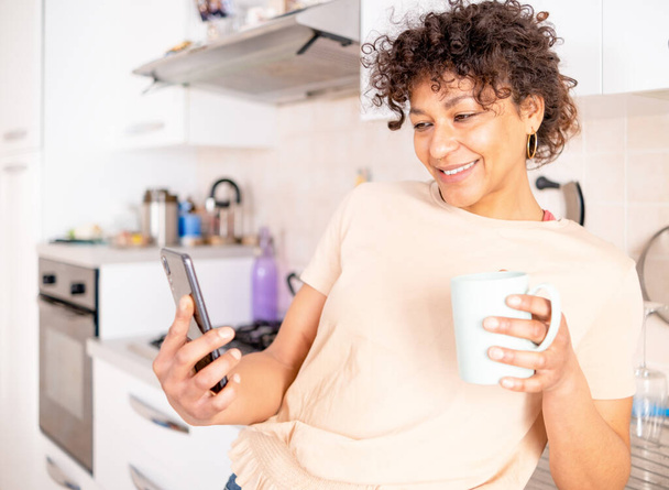 Весела чорна жінка прокручує мобільний телефон вранці вдома
 - Фото, зображення