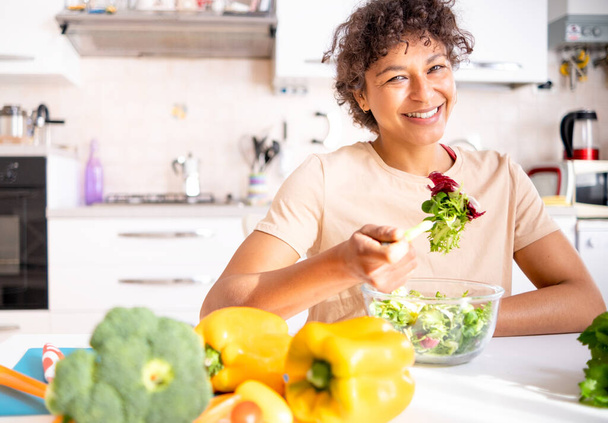 Cheerful black woman eating salad at home ready for diet - Фото, изображение