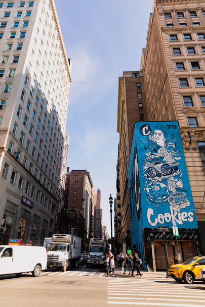 NEW YORK, USA - OCTOBER 13, 2022: pedestrians crossing road near advertising board on corner of building  - Фото, изображение