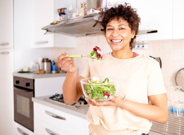 Healthy eating concept. Black woman eating vegetables salad portrait - Fotoğraf, Görsel