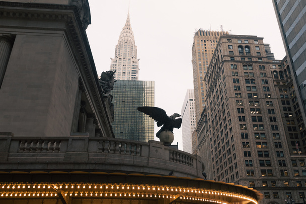 Статуя орла и светящиеся гирлянды на фасаде Центрального вокзала с зданием Chrysler на заднем плане в Нью-Йорке - Фото, изображение
