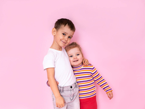 cute kids hugging on a pink background. Brother and sister look at the camera. - Foto, Imagem
