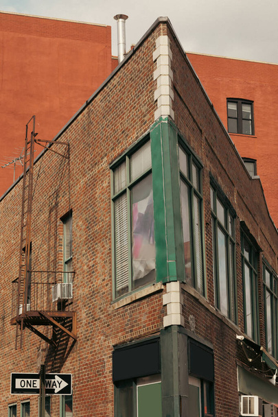 Canto do edifício de tijolos com escada de incêndio na rua em Manhattan  - Foto, Imagem