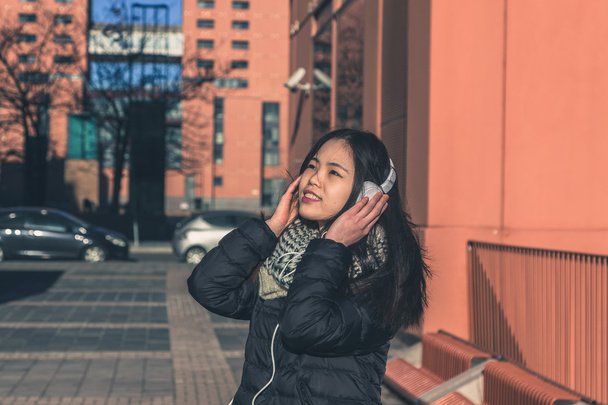 ヘッドフォンで若い美しい中国の女の子 - 写真・画像