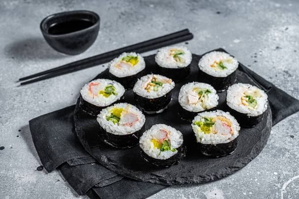 Korean style sushi Kimbap or gimbap made from steamed white rice. Gray background. Top view. - Foto, Imagen