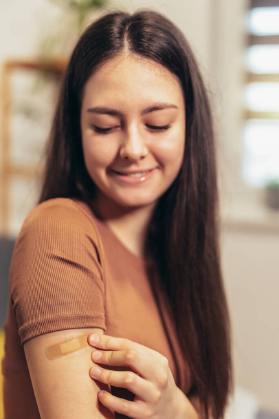 Cheerful teenage girl having plaster on arm .Virus protection. Covid-19 vaccination. HPV vaccine - Φωτογραφία, εικόνα