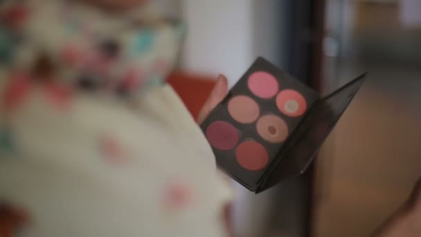 Colored eye shadow palette for cosmetics in hand of make up artist - Video, Çekim