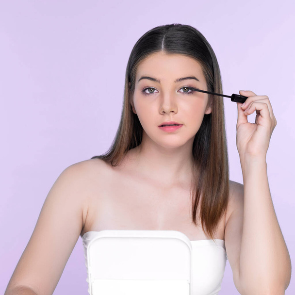 Closeup portrait of young charming applying makeup eyeshadow on her face with brush, mascara with flawless smooth skin for beauty concept. - Zdjęcie, obraz