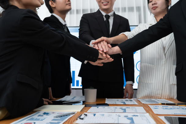 Closeup business team of suit-clad businessmen and women join hand stack together and form circle. Colleague collaborate and work together to promote harmony and teamwork concept in office workplace. - Zdjęcie, obraz