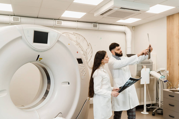I medici di TAC stanno discutendo la radiografia della tomografia computerizzata dei cervelli del paziente. I medici di tomografia computerizzata stanno consultando e discutendo i raggi X del paziente - Foto, immagini