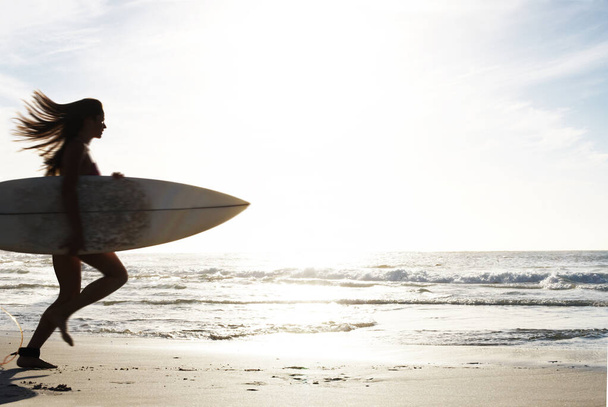 Professionelle Surferin beim Surfen. Porträt einer jungen Frau, die mit einem Surfbrett in Richtung Meer läuft - Foto, Bild