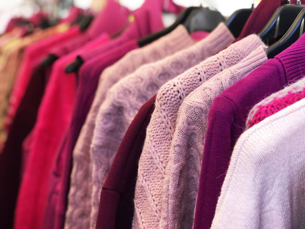 Pink and red clothes hanging in second hand store - Фото, изображение