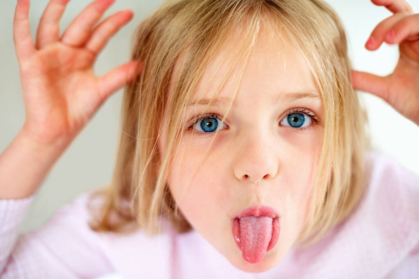 Непослушная молодая девушка показывает свой язык. Крупный план портрета непослушной девочки, показывающей свой язык - Фото, изображение