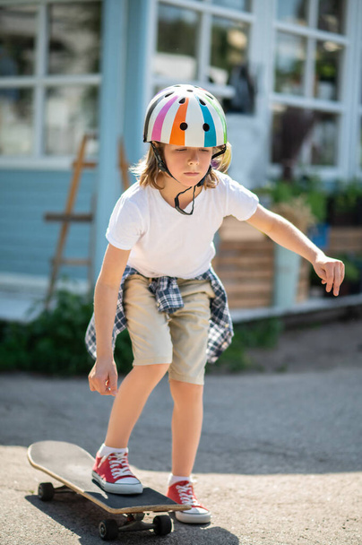 Full-size portrait of a serious preteen boy in the protective helmet stepping on the skateboard - Φωτογραφία, εικόνα