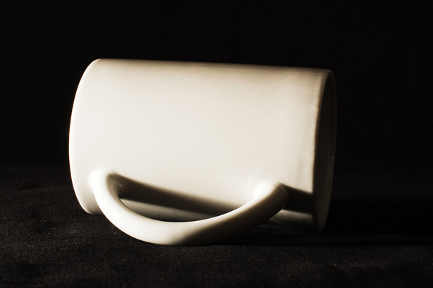 auf dunklem Hintergrund liegender weißer Kaffeebecher - Foto, Bild