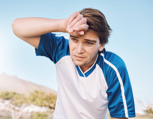 Man, tired with face and soccer player on outdoor field, playing game or football training with energy and exhausted athlete. Team sport, sweating and fitness, challenge and fatigue with workout. - Photo, Image