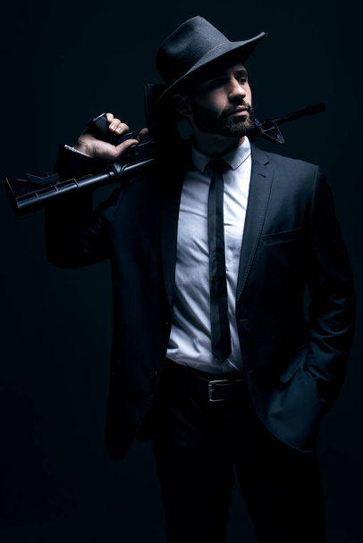 Hitman, suit or holding gun on studio background in dark secret spy, isolated mafia leadership or crime lord security. Model, man or gangster weapon in formal, fashion clothes or bodyguard aesthetic. - Foto, Imagem