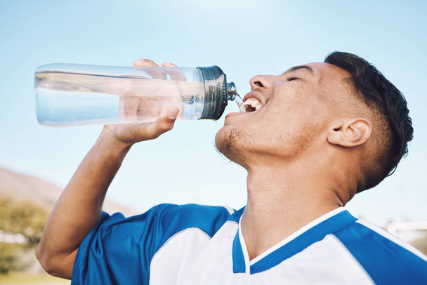 Water, bottle and football or soccer player on sports field resting after match or competition on a sunny day. Man, athlete and sportsman refreshing during a game happy and smiling for fitness. - Foto, Imagem