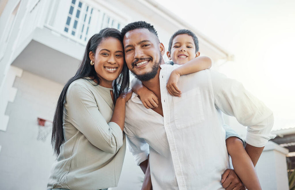 Mother, father and child with smile for new home, property or real estate family time outside the house. Portrait of happy mom, dad and son on piggyback smiling in happiness for apartment building. - Foto, immagini