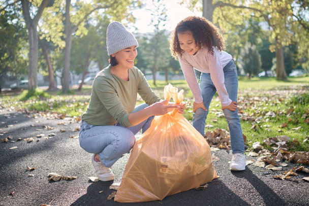 Trash, volunteer woman and kid cleaning garbage, pollution or waste product for environment community service. Plastic bag container, NGO charity and eco friendly child help with nature park clean up. - 写真・画像