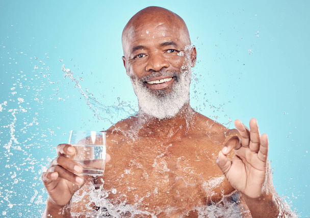 Splash, portrait and elderly man in a studio with a glass of water and a ok hand gesture. Health, wellness and happy senior African male with sign language by a blue background with mockup space. - Foto, Bild