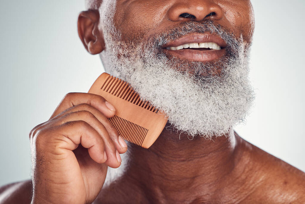 Grooming, comb and barber with beard of black man for beauty, hygiene and skincare. Self care, facial hair and maintenance with senior model for health, wellness and cleaning in studio background. - Photo, Image