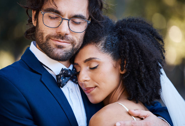 Interracial couple, wedding and hug for love at marriage celebration event with commitment. Happy married man and woman together with trust, partnership and support or care with safety and security. - Photo, image