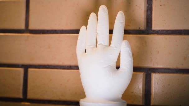 Close-up of a medical glove instead of a water seal when fermenting wine. An inflated white latex glove against a coffee-colored decorative brick wall. Raised hand, smooth parallax. High quality - Πλάνα, βίντεο