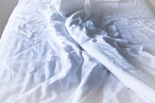 Κρεβάτι και λευκά φύλλα τσαλακωμένα μετά το ξύπνημα - Φωτογραφία, εικόνα