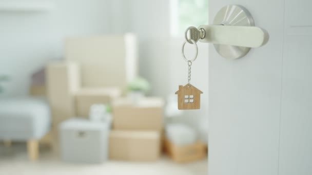 Moving house, relocation. The key was inserted into the door of the new house, inside the room was a cardboard box containing personal belongings and furniture. move in the apartment or condominium - Imágenes, Vídeo