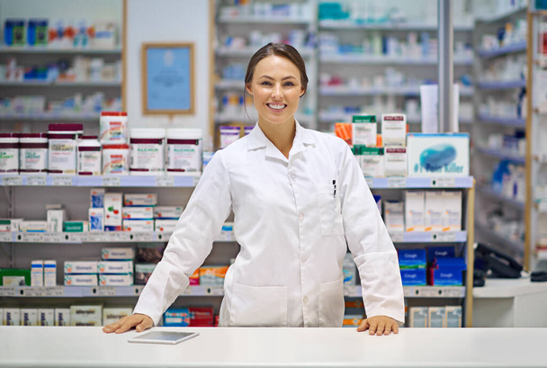 Your friendly and experienced local pharmacist. Portrait of an attractive young pharmacist standing at the prescription counter - Foto, imagen