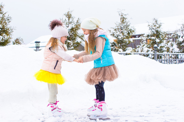 Маленькі дівчата катаються на ковзанах на відкритому повітрі в зимовий день снігу
 - Фото, зображення