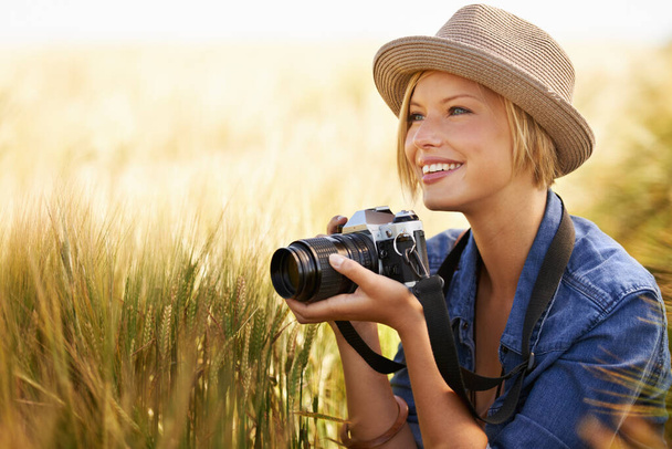 Photographier la beauté de la nature. Une jeune femme séduisante tenant une caméra alors qu'elle était accroupie à côté d'un copyspace dans un champ - Photo, image