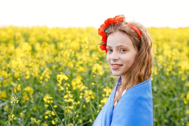 Bid voor Oekraïne. Kind met Oekraïense vlag in koolzaadveld. Meisje met nationale vlag biddend voor vrede. - Foto, afbeelding