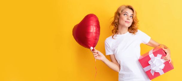 glimlachende roodharige vrouw met rode hartballon en geschenkdoos. Wees mijn Valentijn. Schoonheid vrouw geïsoleerd gezicht portret, banner met mock up kopieerruimte - Foto, afbeelding