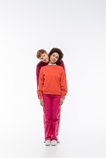 cheerful interracial couple in magenta color clothes showing i letter on white background  - Foto, Bild