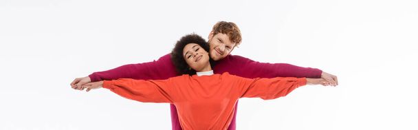 happy and interracial couple in magenta color clothes holding hands on white background, banner  - Photo, image