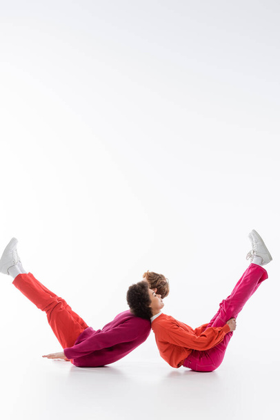 Seitenansicht eines gemischtrassigen Paares in magentafarbener Kleidung, die einen Buchstaben auf weißem Hintergrund zeigt  - Foto, Bild