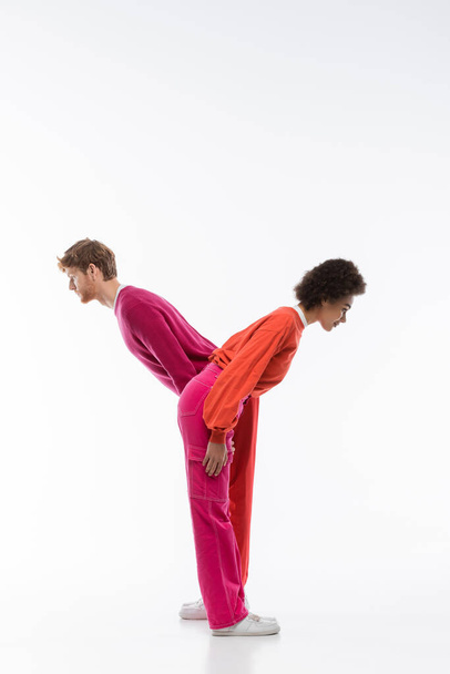side view of interracial couple in magenta color clothes showing y letter on white background  - Φωτογραφία, εικόνα
