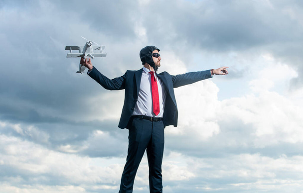 businessman in suit and pilot hat launch plane toy on sky background. achievement. - 写真・画像