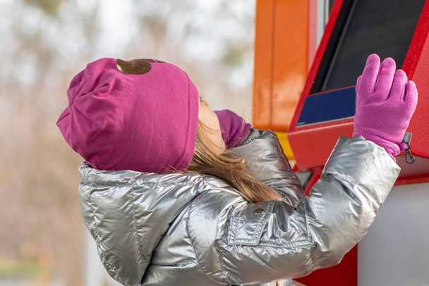 Маленька дівчинка хоче купити квиток на перевезення в торговому автоматі
 - Фото, зображення