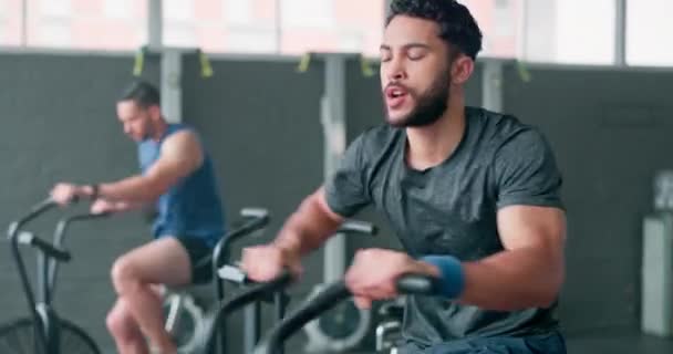 Exercise bike, fitness and sweating with a man athlete in a gym for a cardiovascular workout. Elliptical machine, exercise and breathing with a male cycling to increase health, cardio or endurance. - Felvétel, videó