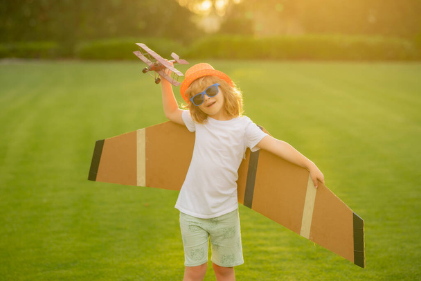 Porträt eines Kindes mit Spielzeugpapierflügeln im Freien. Erfolgreiches, kreatives und Start-up-Konzept - Foto, Bild
