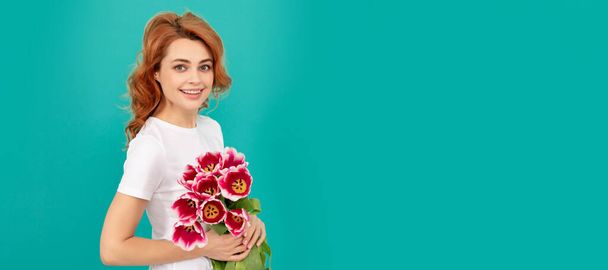 smiling girl with tulip flower bouquet on blue background. Woman isolated face portrait, banner with mock up copyspace - Zdjęcie, obraz