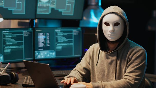 Hacker com máscara anônima quebrando sistema de segurança, instalando vírus para criar malware computador e roubar dados on-line. Mascarado criminoso scammer hacking servidor de rede tarde da noite. - Foto, Imagem