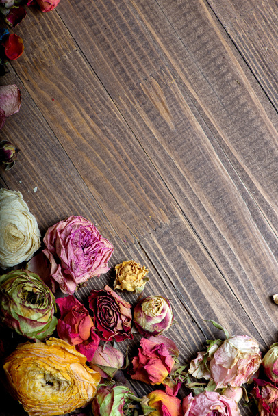 Marco de vacaciones abstracto con pétalos de rosa y flores secas en platos de madera viejos
. - Foto, Imagen