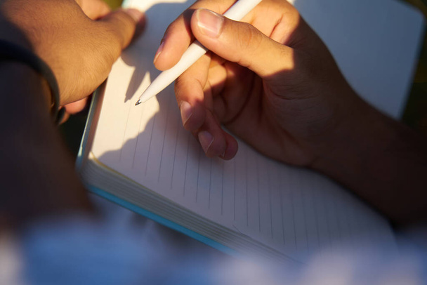 Ręce z bliska trzymające długopis, notatki w notatniku, selektywne skupienie. Koncepcja edukacji  - Zdjęcie, obraz