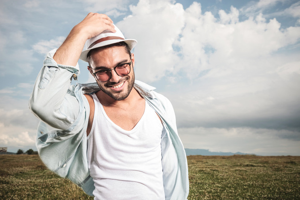 Sonriente joven hombre de la moda sosteniendo su sombrero
 - Foto, imagen